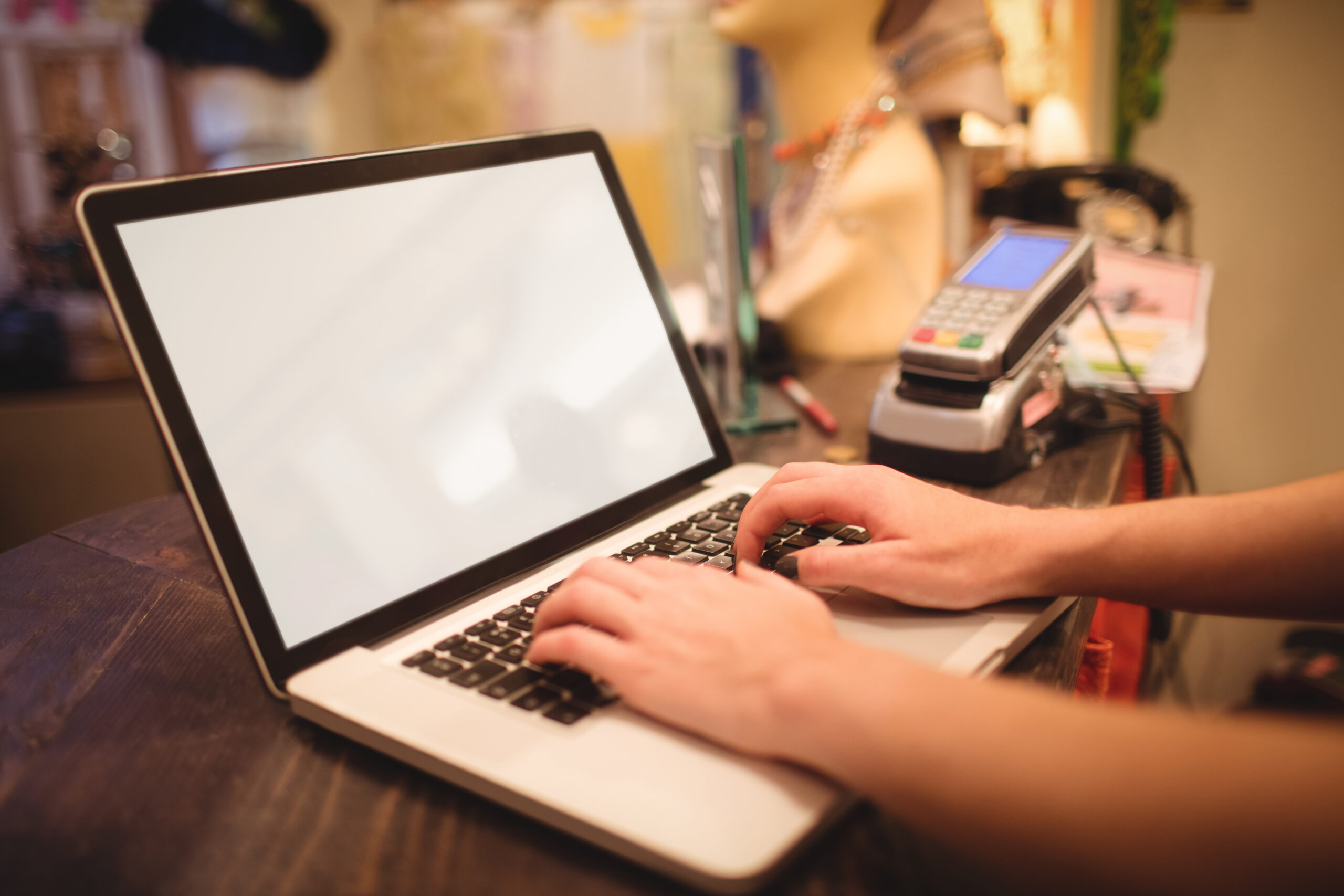 Hands of female staff using laptop at a counter in boutique store